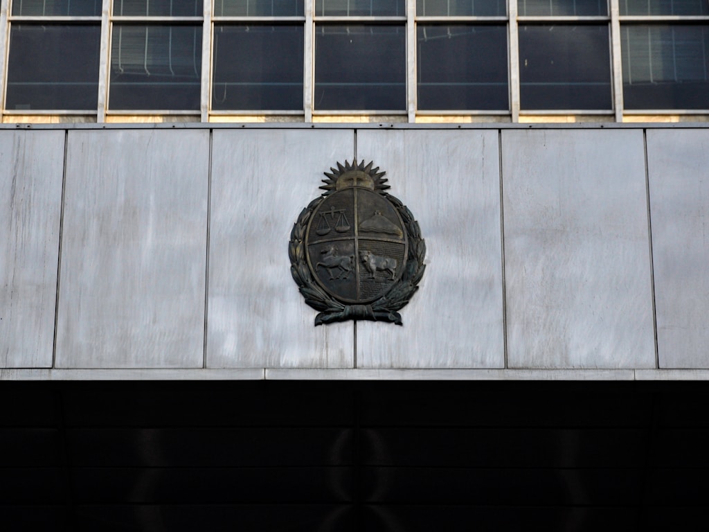 Bronze coat of arms with scales of justice and laurel wreath on a marble building facade