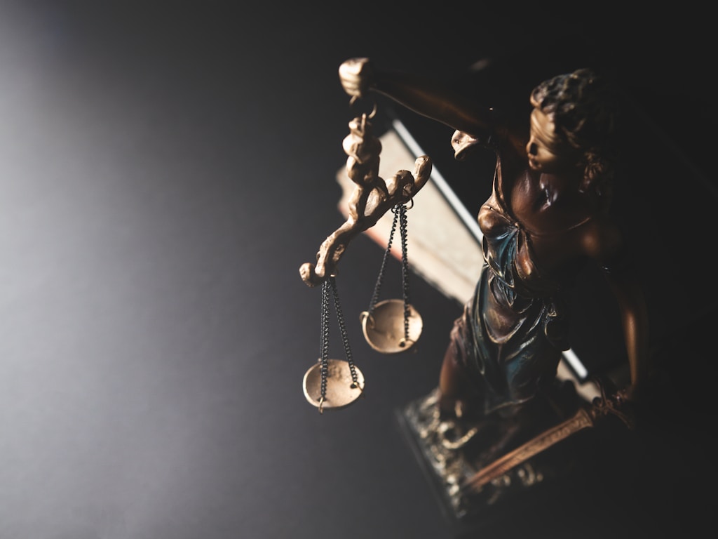 Bronze statue of Lady Justice holding scales in dramatic low-key lighting